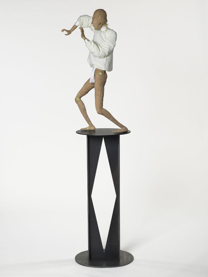A sculptural work depicting a man with rubbery features; he wears white and appears to be dancing.